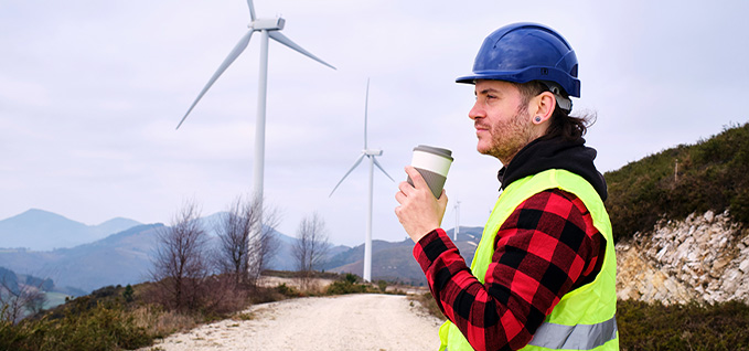 Mobil engineer on wind farm taking a coffee break